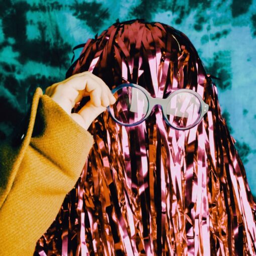 Woman posing for a school photo in a pom pom wig and glasses